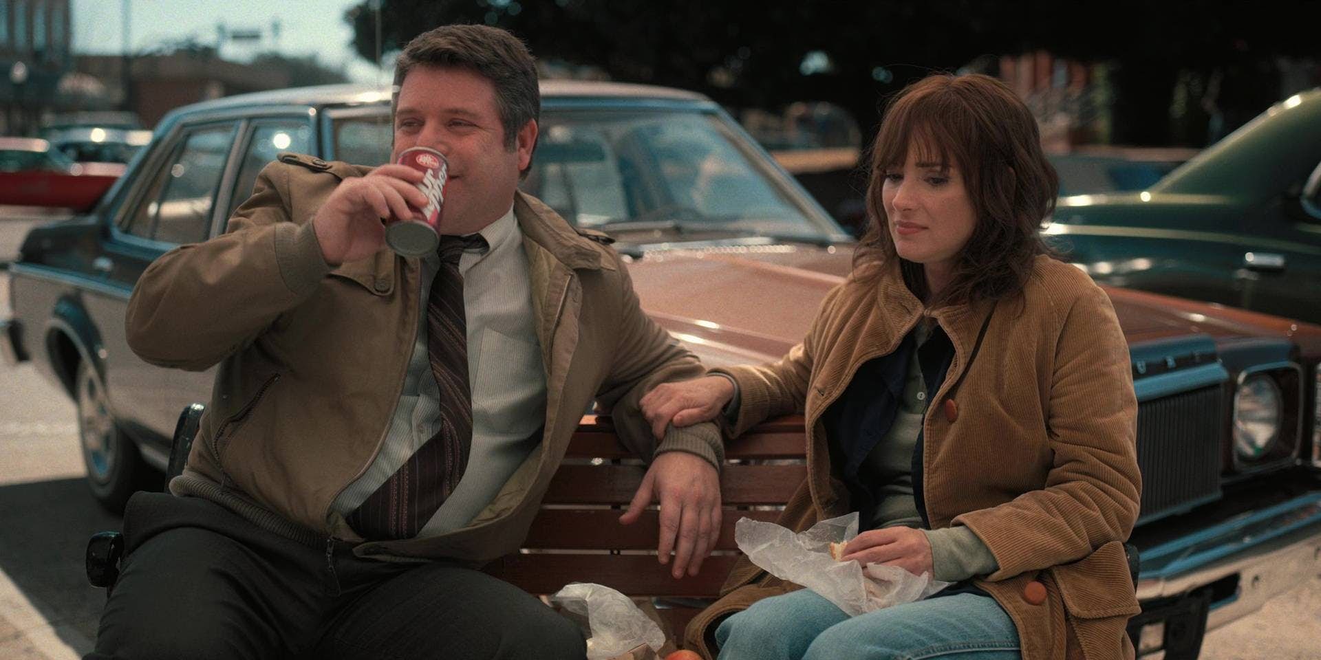 Bob from "Stranger Things" drinking Dr. Pepper on a bench next to Joyce Byers