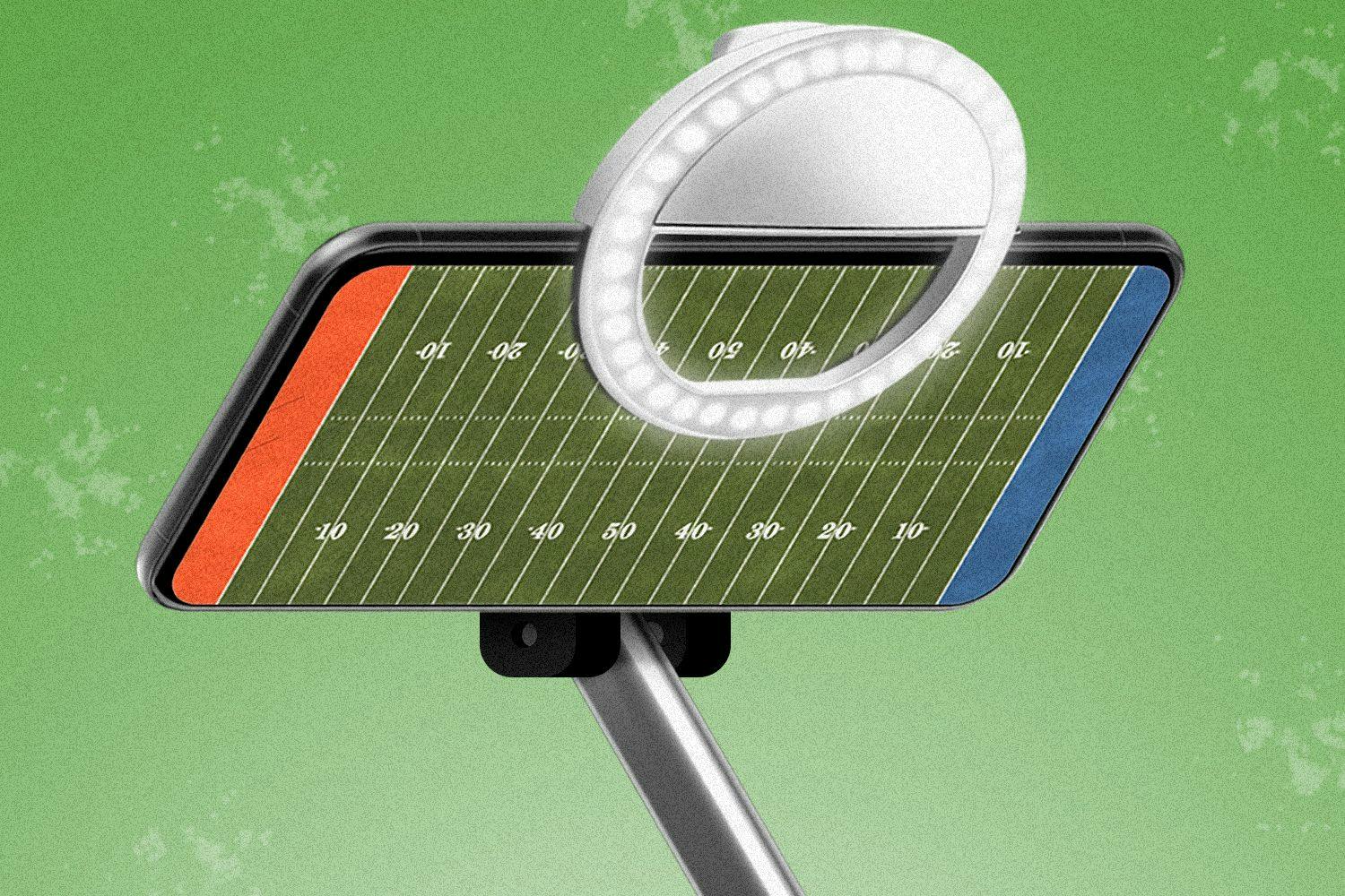 a phone with a football field on the screen. the phone is in a selfie stick / ring light
